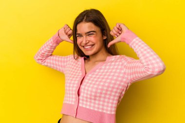 Sarı arka planda izole genç beyaz kadın gururlu ve kendinden emin hissediyor, örnek olarak..