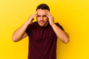 Sarı arka planda izole edilmiş genç beyaz adam tapınaklara dokunuyor ve baş ağrısı çekiyor..