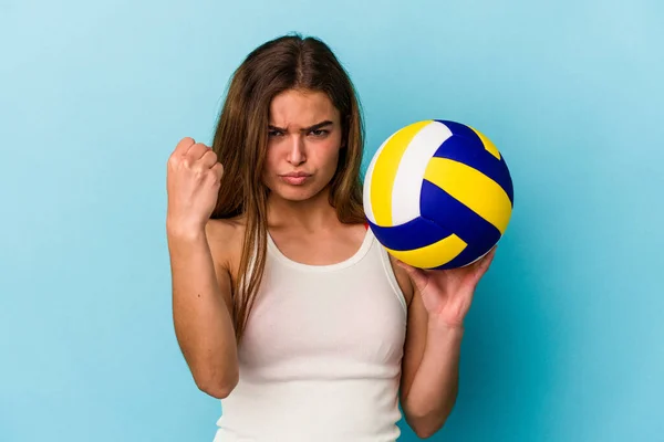年轻的高加索女子打排球时 背景是蓝色 对着镜头 表情咄咄逼人 — 图库照片