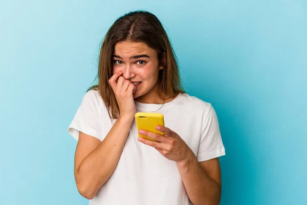 Mujer Caucásica Joven Sosteniendo Teléfono Móvil Aislado Sobre Fondo Azul — Foto de Stock