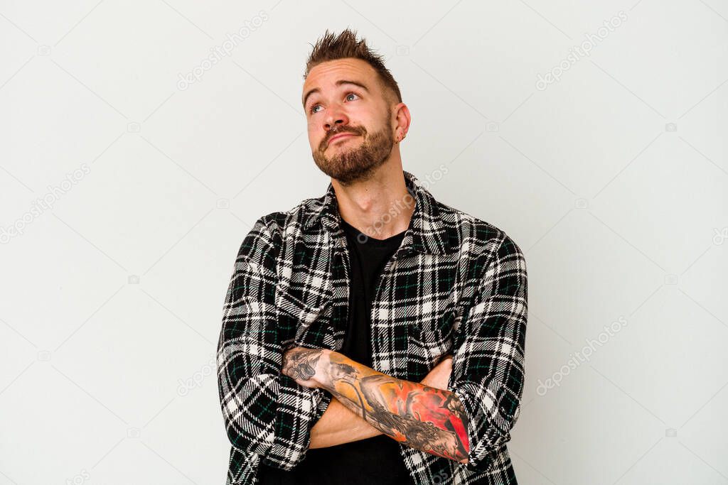 Young tattooed caucasian man isolated on white background dreaming of achieving goals and purposes