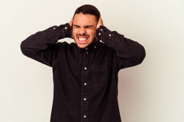 Beyaz arka planda izole edilmiş genç beyaz bir adam kulaklarını elleriyle kapatıyor..