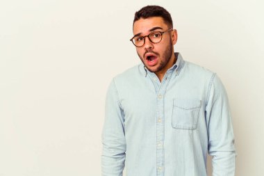 Beyaz arka planda izole edilmiş genç beyaz adam gördüğü bir şey yüzünden şoka uğruyor..