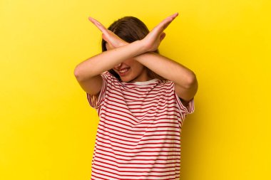 Sarı arka planda izole edilmiş genç beyaz kadın iki kolu çapraz tutuyor, inkar kavramı.