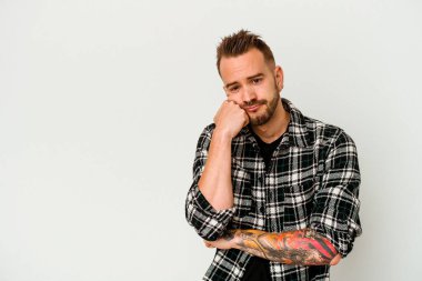 Beyaz arka planda izole edilmiş genç dövmeli beyaz adam üzgün ve dalgın hisseder, kopyalama alanına bakar..