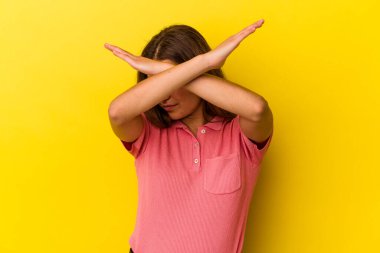 Sarı arka planda izole edilmiş genç beyaz kadın iki kolu çapraz tutuyor, inkar kavramı.