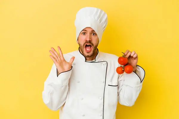 Mladý Kavkazský Kuchař Muž Drží Rajčata Izolované Žlutém Pozadí Překvapené — Stock fotografie