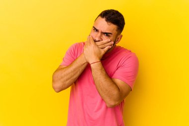 Sarı arka planda izole edilmiş genç beyaz adam elleri endişeli bir şekilde ağzı örtüyor..