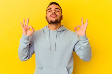 Sarı arka planda izole edilmiş genç beyaz adam sıkı çalışma gününden sonra rahatlıyor. Yoga yapıyor..