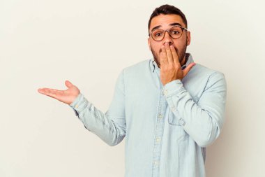 Beyaz arka planda izole edilmiş genç beyaz adam, avuç içi fotokopi alanını elinde tutmaktan etkilenmiş..