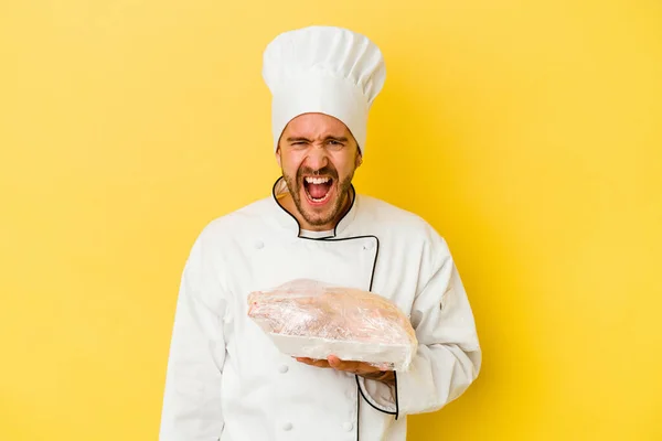 Mladý Kavkazský Kuchař Muž Drží Kuře Izolované Žlutém Pozadí Křičí — Stock fotografie