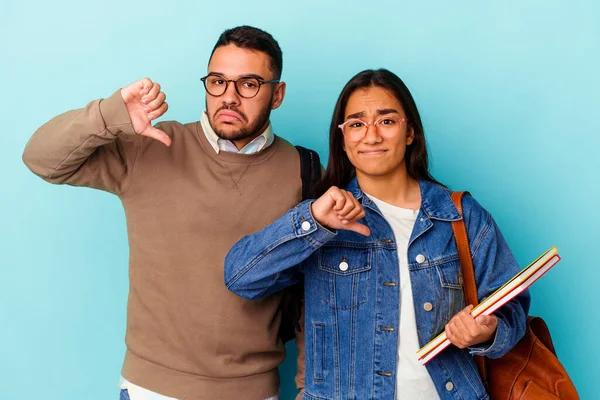 Jonge Gemengde Ras Student Paar Geïsoleerd Blauwe Achtergrond Toont Een — Stockfoto