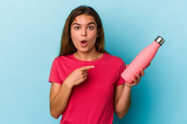 Mavi arka planda izole edilmiş su şişesi tutan beyaz bir kadın var.