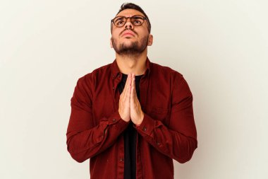 Beyaz arka planda izole edilmiş genç beyaz bir adam el ele tutuşup, ağız kenarında dua ediyor, kendinden emin..