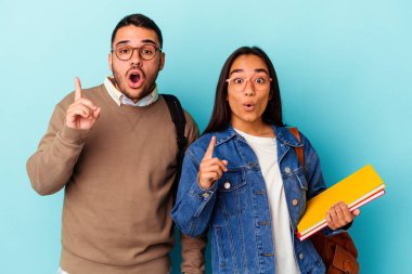 Mavi arka planda soyutlanmış genç melez bir çift yaratıcılık kavramına sahipler..