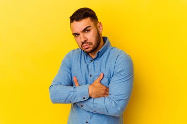 Sarı arka planda izole edilmiş genç beyaz adam alaycı bir ifadeyle kameraya bakıyor..