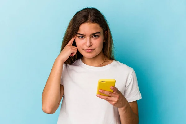 Młoda Kaukaska Kobieta Trzyma Telefon Komórkowy Odizolowany Niebieskim Tle Wskazując — Zdjęcie stockowe