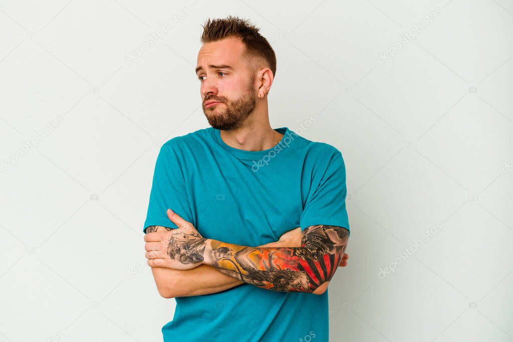 Young tattooed caucasian man isolated on white background tired of a repetitive task.