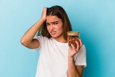 Mavi arka planda izole edilmiş bir badem kavanozu tutan genç beyaz kadın şok geçiriyordu. Önemli bir toplantıyı hatırladı..