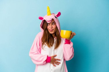 Kafkasyalı genç bir kadın tek boynuzlu at kostümü giyiyor ve elinde bir kupa tutuyor.