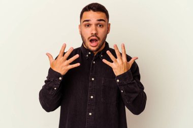 Beyaz arka planda izole edilmiş beyaz tenli genç adam on numarayı elleriyle gösteriyor..