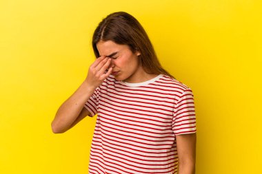 Sarı arka planda izole edilmiş, başı ağrıyan, yüzünün ön kısmına dokunan beyaz bir kadın..