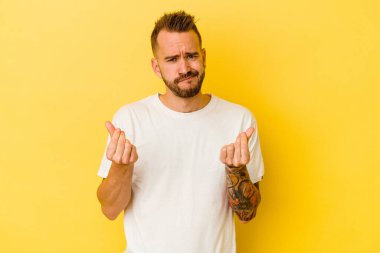 Sarı arka planda izole edilmiş genç dövmeli beyaz adam, kadının hiç parası olmadığını gösteriyor..