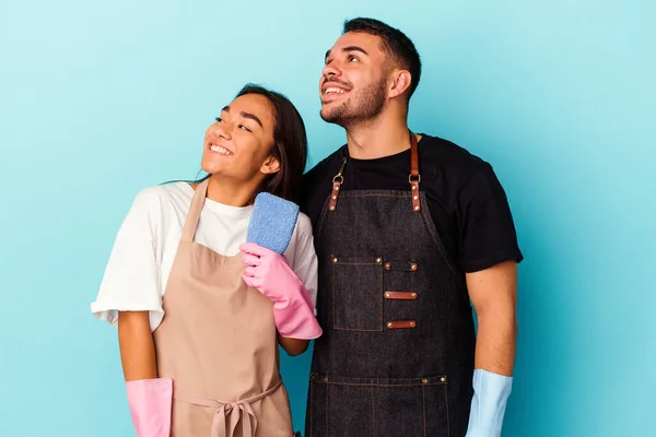 Young Mixed Race Couple Cleaning Home Isolated Blue Background Dreaming — Stock Photo, Image