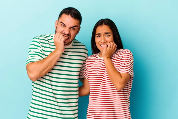 Joven Pareja Mestiza Aislada Sobre Fondo Azul Mordiendo Las Uñas — Foto de Stock