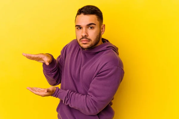 Homem Caucasiano Jovem Isolado Fundo Amarelo Segurando Algo Com Ambas — Fotografia de Stock