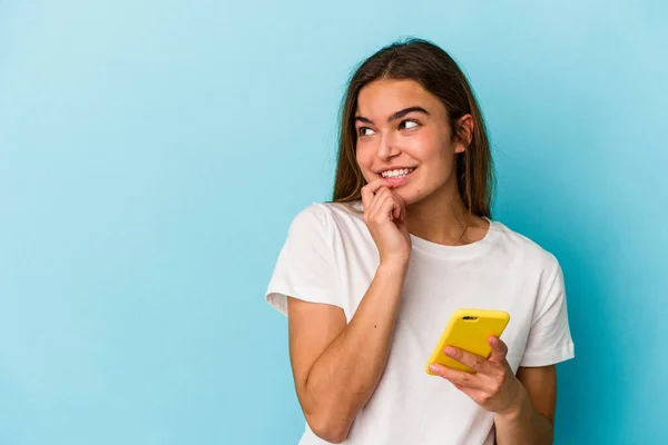 Joven Mujer Caucásica Sosteniendo Teléfono Móvil Aislado Sobre Fondo Azul — Foto de Stock