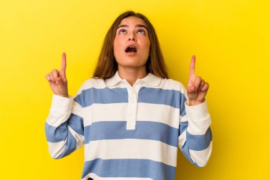 Sarı arka planda izole edilmiş beyaz bir kadın ağzı açık bir şekilde üst tarafı işaret ediyor..