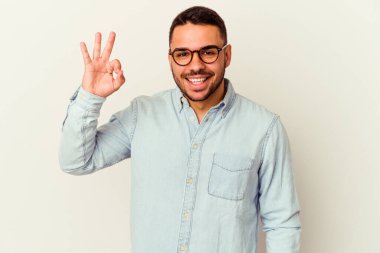 Beyaz arka planda izole edilmiş genç beyaz bir adam bir göz kırptı ve elleriyle iyi bir jest yaptı..