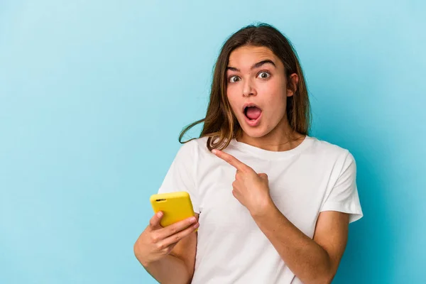 Joven Mujer Caucásica Sosteniendo Teléfono Móvil Aislado Sobre Fondo Azul — Foto de Stock