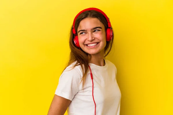 Νεαρή Καυκάσια Γυναίκα Που Ακούει Μουσική Απομονωμένη Κίτρινο Φόντο Ατενίζει — Φωτογραφία Αρχείου