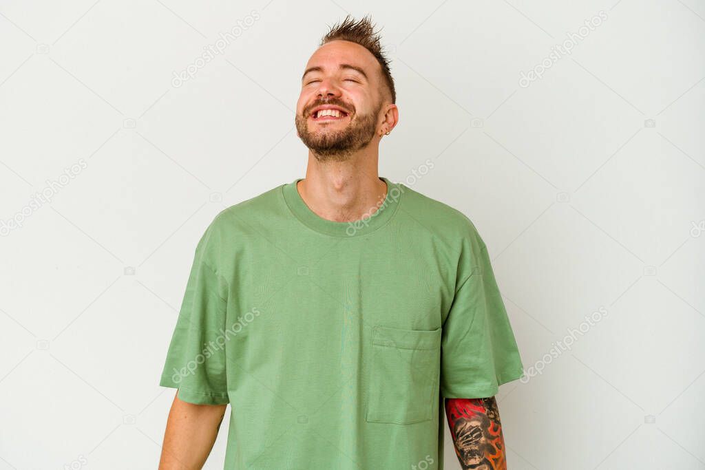 Young tattooed caucasian man isolated on white background laughs and closes eyes, feels relaxed and happy.