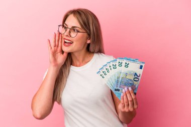Elinde banknotlar tutan genç Rus kadın pembe arka planda izole edilmiş bağırıyor ve avuç içini açık tutuyordu..
