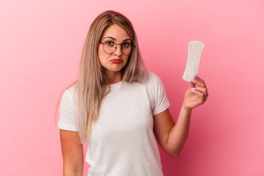 Pembe arka planda izole edilmiş kompres tutan genç Rus kadın omuzlarını silker ve gözleri açık kalır..