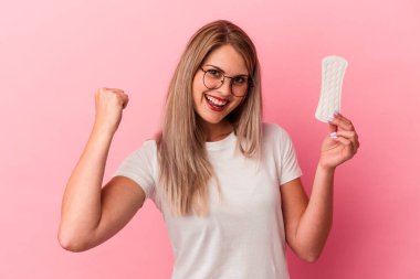 Pembe arka planda bir kompres tutan genç Rus kadın zaferden sonra yumruğunu kaldırıyor, kazanan konsept..