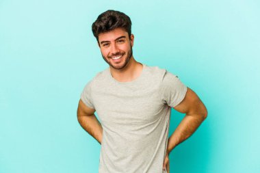 Mavi arka planda izole edilmiş genç beyaz adam mutlu, güler yüzlü ve neşeli.