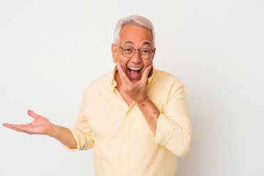 Beyaz arka planda izole edilmiş kıdemli Amerikalı bir adam avuç içinde fotokopi alanı tutuyor, el üstünde tutuyor. Şaşırmış ve mutlu..