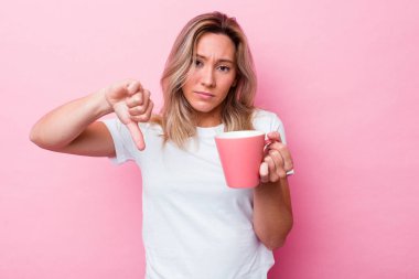 Pembe arka planda pembe bir kupa tutan genç Avustralyalı kadın hoş olmayan bir jest gösteriyor. Anlaşmazlık konsepti.