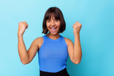 Mavi arka planda soyutlanmış, tasasız ve heyecanlı genç bir ırk kadını. Zafer konsepti.