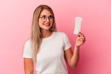 Pembe arka planda bir kompres tutan genç Rus kadın hedeflerine ve amaçlarına ulaşma hayali kuruyor.