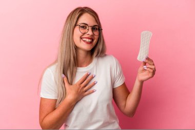 Pembe arka planda izole edilmiş kompres tutan genç Rus kadın kahkahalar atıyor..