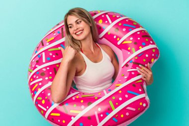 Şişme donutlu genç Rus kadın mavi arka plan noktalarında izole edilmiş başparmak uzakta, gülüyor ve kaygısız.