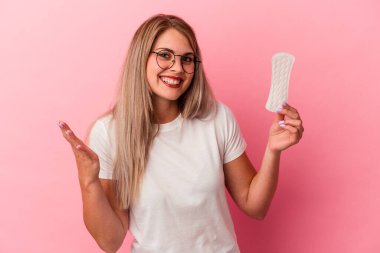 Pembe arka planda bir kompres tutan genç Rus kadın hoş bir sürprizle karşılaşıyor, heyecanlı ve el kaldırıyor..