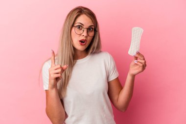 Pembe arka planda izole edilmiş kompres tutan genç bir Rus kadının harika bir fikri var, yaratıcılık kavramı..