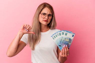 Elinde pembe arka planda izole edilmiş banknotlar tutan genç Rus kadın hoşlanmadığı bir jest gösteriyor. Anlaşmazlık konsepti.