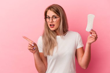 Pembe arka planda bir kompres tutan genç Rus kadın yan tarafı işaret ediyor.